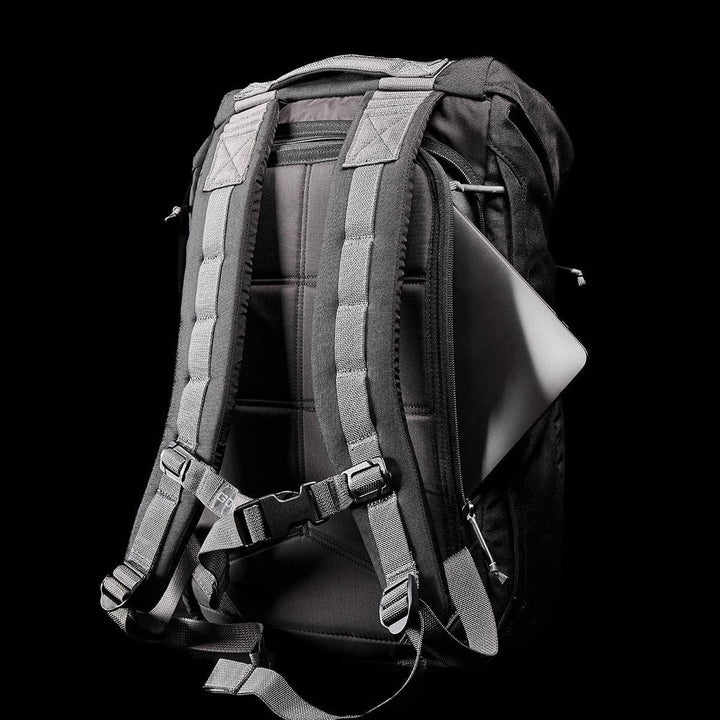 A black GORUCK M23 - Cordura rucksack with padded straps displays a laptop partially visible in a compartment against a dark background, crafted from durable materials for everyday use.