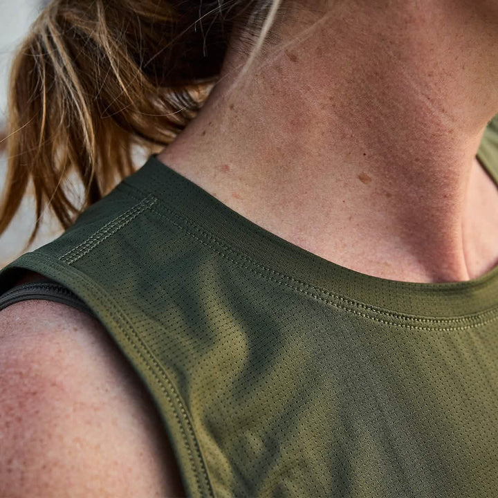 Close-up of a person wearing the Women’s Performance Tank - ToughMesh by GORUCK in olive green. The image focuses on the shoulder and neck area, highlighting the unique texture of the material and the person's skin. Brown hair is partially visible in the frame.