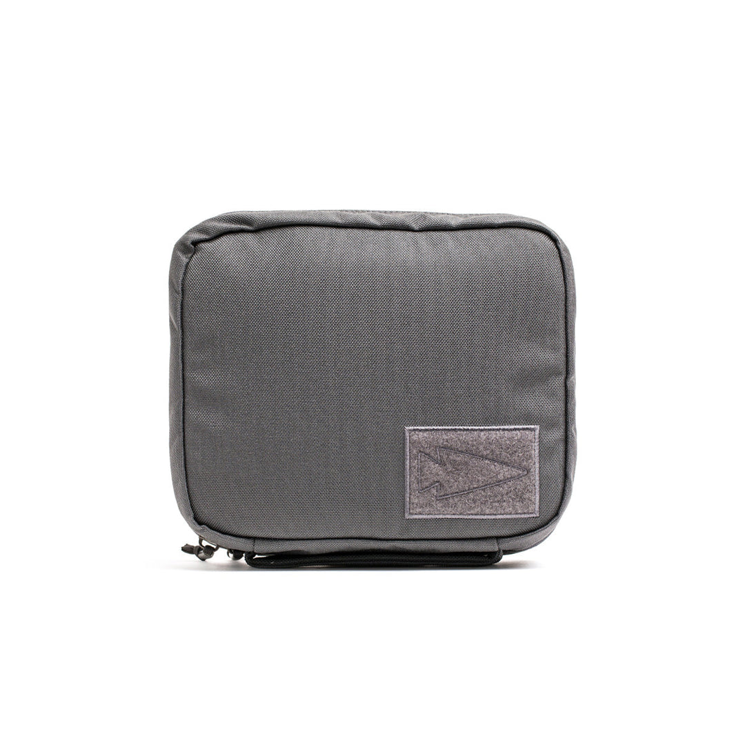 The GR2 Field Pocket is a durable gray fabric pouch made of 1000D Cordura, featuring a zipper and a small front logo patch, ideal for organizing electronics.