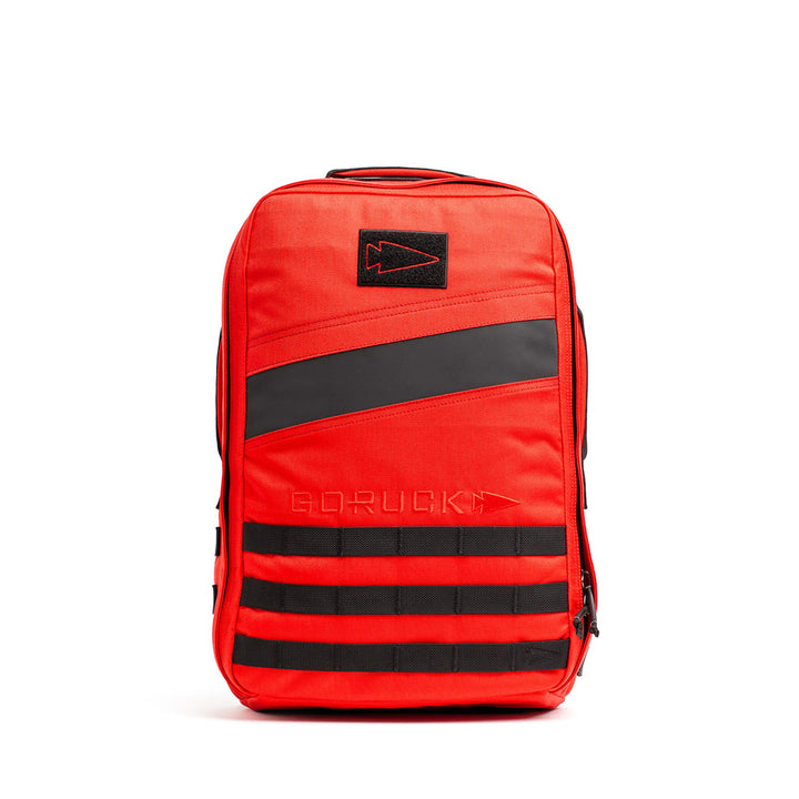 The GORUCK Rucker 4.0 is a red and black backpack with a minimalist design, featuring horizontal black straps at the bottom. Ideal for rucking, this streamlined pack is Ruck Plate® compatible for enhanced functionality.