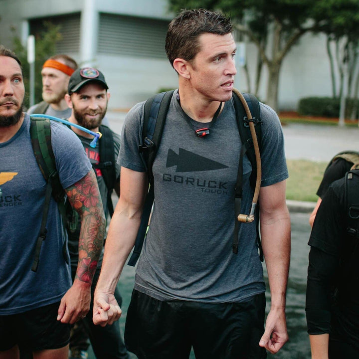 A group of people in athletic gear participates in an outdoor event, with one man prominently in focus. He's using the Source Hydration Bladder, a state-of-the-art system that prioritizes peak performance and health.