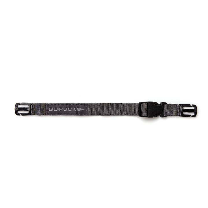 The GORUCK Training Sternum Strap in gray has adjustable black buckles on each end for weight distribution and integrates seamlessly with MOLLE webbing, shown laid flat against a white background.