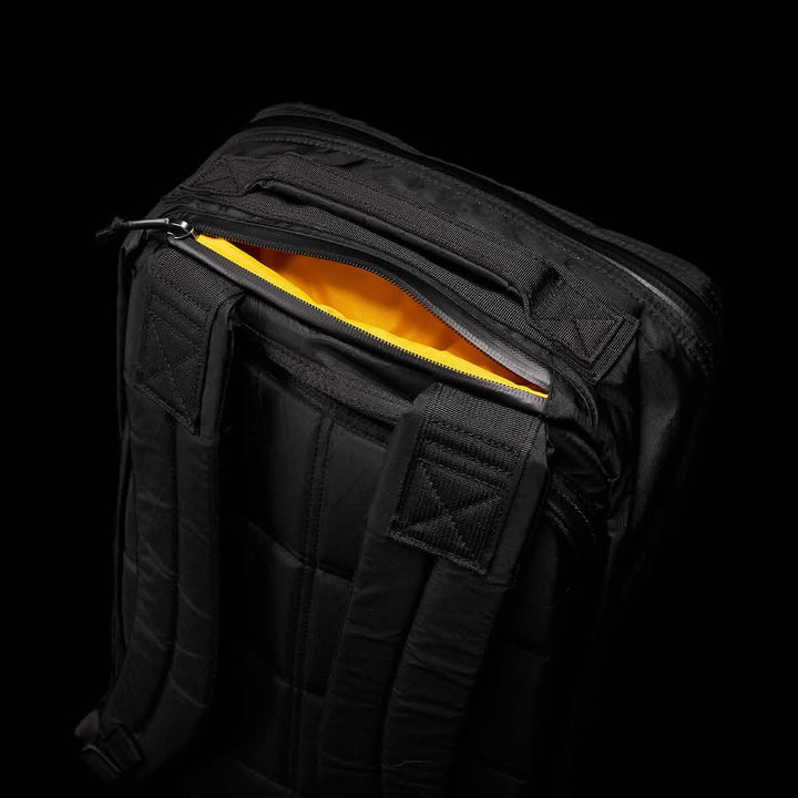 The GORUCK GR1 USA - X-PAC is a black backpack with a visible yellow interior, padded straps, and AquaGuard zippers for water resistance.