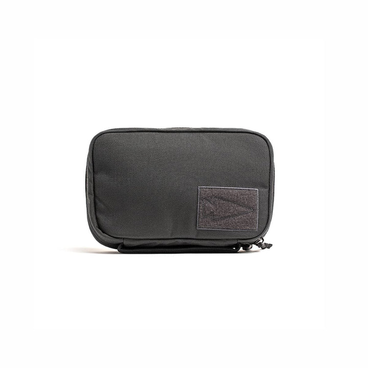 The GR1 Field Pocket by GORUCK is a black rectangular zippered pouch with a patch on the front, ideal for organizing electronics.