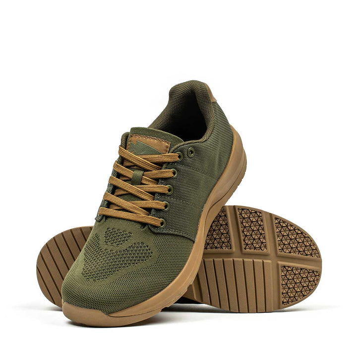 Introducing the Ballistic Trainers - Green + Gum from GORUCK: sneakers in olive green with tan soles crafted from durable CORDURA® Ballistic Nylon. One shoe stands upright, highlighting its sleek design, while the other lays on its side to showcase a distinctive tread pattern. These trainers are ideal as functional fitness footwear with 3X Stability support.