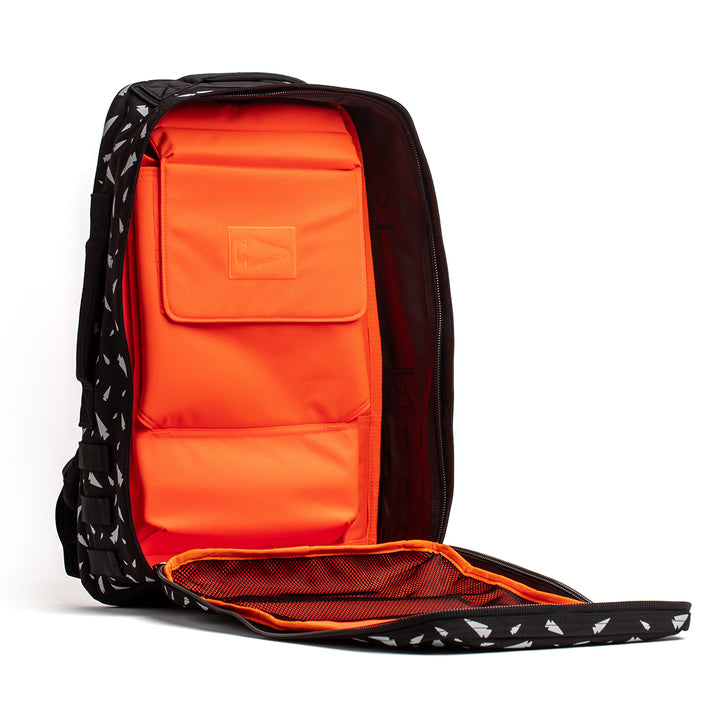 The stylish black GORUCK Rucker 4.0 showcases an open front that reveals an orange padded interior with multiple compartments. Perfect for daily use or adventurous outings, this design merges practicality with elegance.