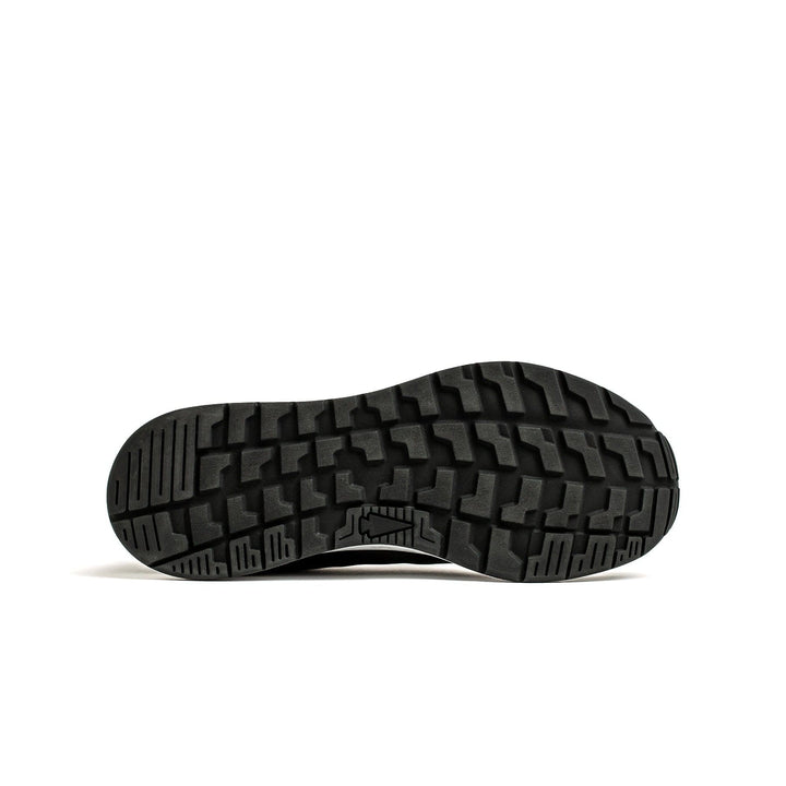 The image displays the underside of the Men's Rough Runner - Black + White shoe by GORUCK, featuring a textured sole with a deep tread pattern for excellent grip and traction. Positioned on a white background, this lightweight running shoe includes a Gradient Density EVA Midsole to enhance comfort.