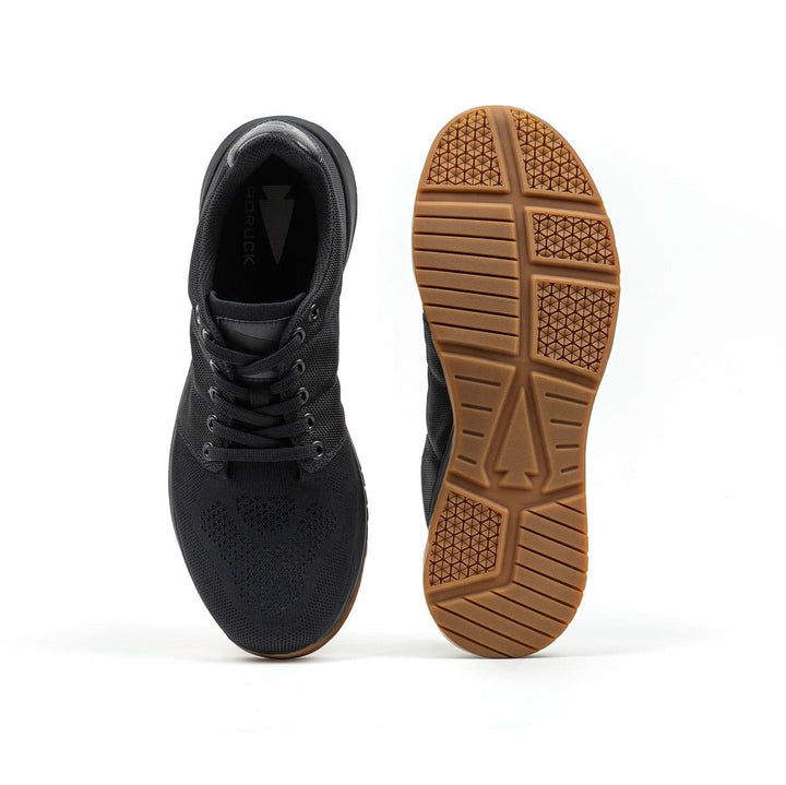 The Ballistic Trainers - Black + Gum by GORUCK feature durable CORDURA® Ballistic Nylon construction with textured brown soles; one shoe is upright to highlight its 3X Support design, while the other displays the sole, making them ideal for functional fitness footwear enthusiasts.