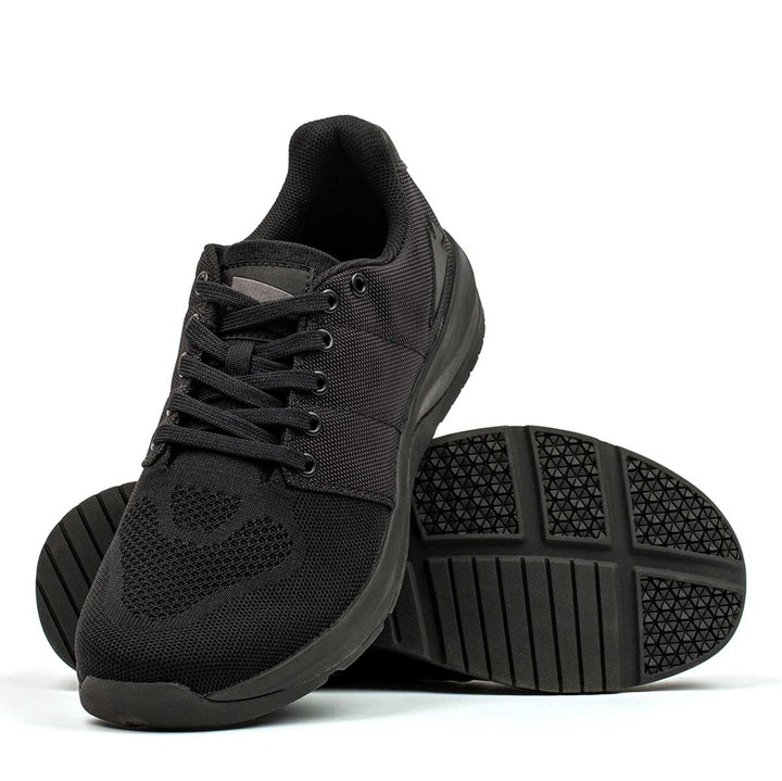 A pair of Ballistic Trainers - Blackout w/ Black Reflective Spearhead by GORUCK, featuring textured soles, one propped on the other to highlight functional fitness footwear crafted with CORDURA® Ballistic Nylon for enhanced durability.