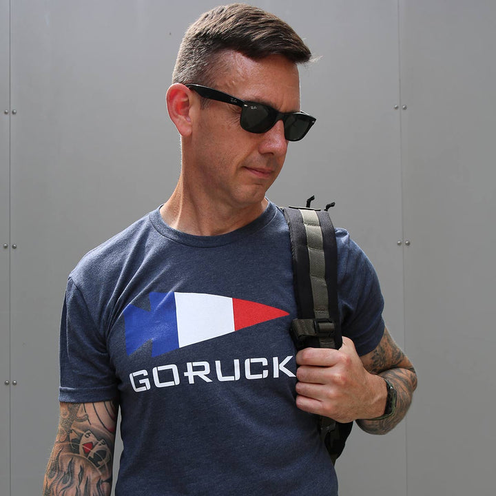 Man with sunglasses and tattoos styled in a GORUCK EU T-shirt - Rep Your Country, effortlessly cool while carrying a backpack.