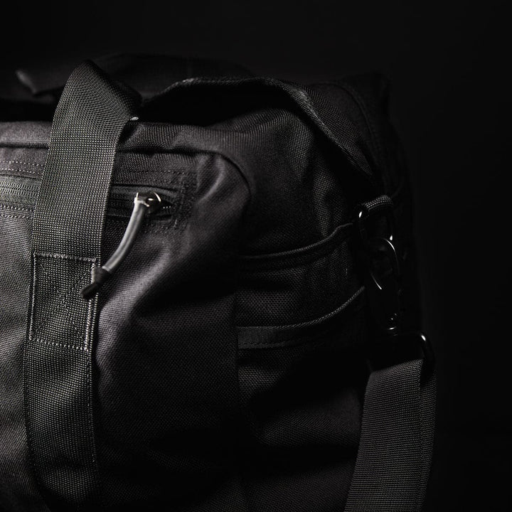 The Kit Bag by GORUCK is a black duffel designed to resemble a Special Forces Flight Bag, featuring sturdy handles and zippers, highlighted against a dark background.