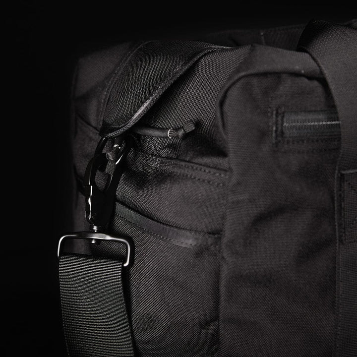 Close-up of a black GORUCK Kit Bag featuring a strap and metal buckle against a dark background.