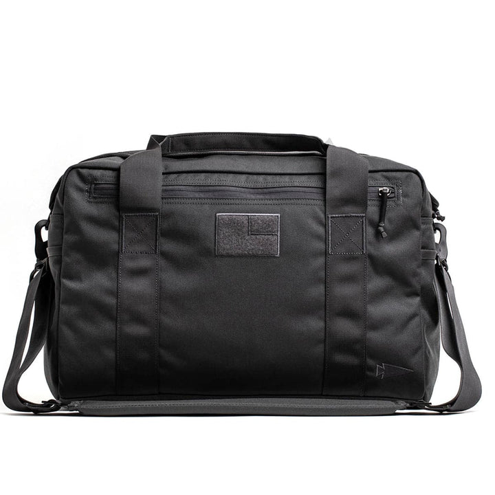 Introducing the GORUCK Kit Bag—a sleek, black rectangular bag equipped with convenient dual handles and an adjustable shoulder strap. Designed with multiple zippers and a textured patch on the front, this minimalist and functional accessory is ideal for both travel and daily use.