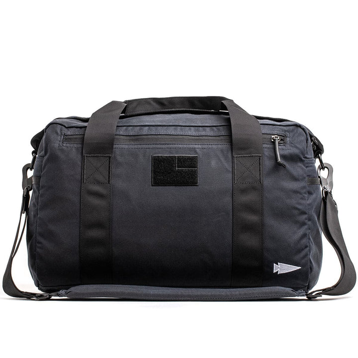 The Kit Bag - Waxed Canvas by GORUCK is a black duffel bag featuring short handles and a detachable shoulder strap, inspired by the classic Aviator's Kit Bag.