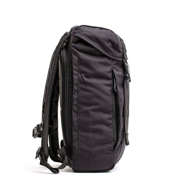 A side view of the black, sleek GORUCK M23 - Cordura rucksack reveals its adjustable shoulder straps and multiple zippered compartments. Crafted from durable materials, its minimalist and modern design seamlessly complements any style.