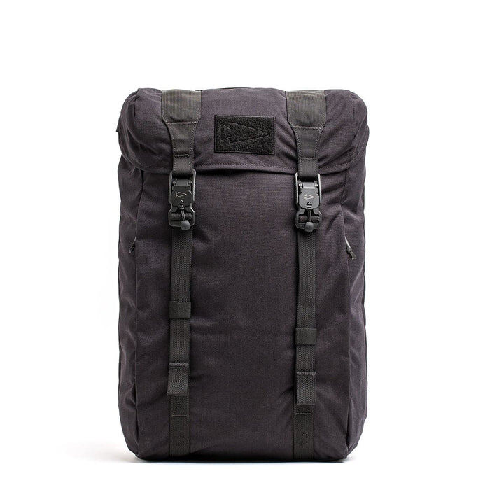 The M23 - Cordura by GORUCK is a black tactical backpack designed with durable materials, complete with two buckle straps and buttoned flaps on the front. It features a top handle and multiple compartments, offering a modern yet rugged look ideal for outdoor adventures.