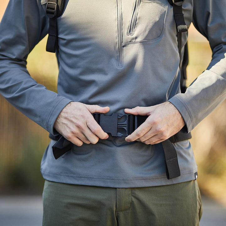 A person skillfully secures a black buckle on the GORUCK Padded Hip Belt outdoors, designed with durable CORDURA fabric.