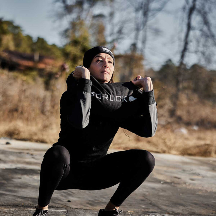 A person in a beanie and winter activewear is performing squats outdoors, utilizing Simple Training Sandbags by GORUCK for extra resistance.