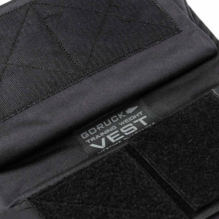 Close-up of a black Training Weight Vest by GORUCK featuring adjustable Velcro straps and a visible brand label.